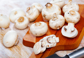 Close-up of cut fresh raw champignons on wooden desk