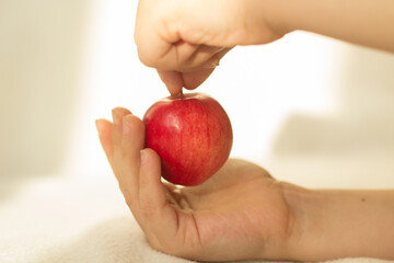 A small red Apple in children's hands. Tenderness.