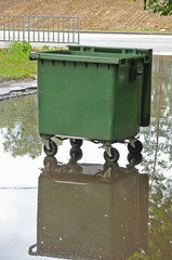 garbage container in the middle of a large puddle after heavy rain