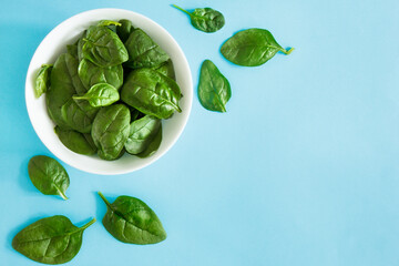 Fresh spinach in a bowl on a blue background