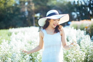 Young beautiful woman in a white dress posing in white flower garden