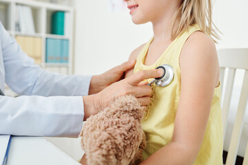 Cropped image of pediatritian listening to heartbeat of little girl