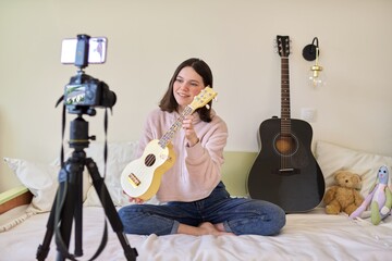 Teenager girl plays music on ukulele, online learning and chatting with followers