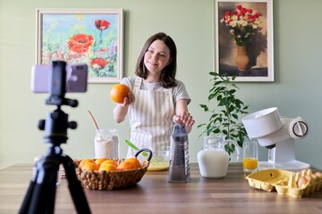 Obraz na płótnie Canvas Girl teenager food blogger recording recipe for cooking orange pancakes