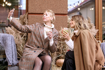 two women drink hot tea while sitting at a table in a restaurant and chatting