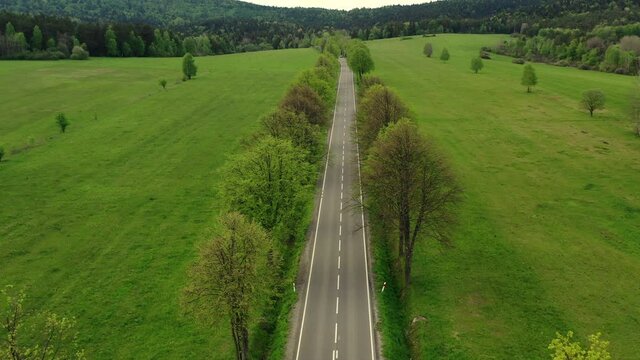 Aerial View Of Rural Road With Hills Trees And Field Of Green Grass In Summer. 