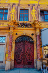 Wroclaw, Poland - 2012: Yellow stucco arc with beautifully decorated red wooden door with curve decor.