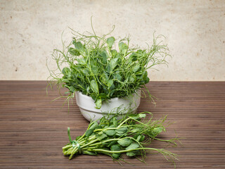 A round ceramic pot with freshly picked microgreens (pea sprouts).