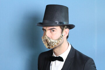 Gentleman in a tuxedo wearing golden face mask 
