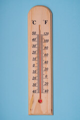 Classic wooden thermometer for measuring temperature on a blue background. Close-up.
