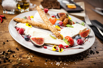 Cheese platter for two: Goat cheese cream, gorgonzola, camembert, grissini and fig jam. Delicious healthy Italian traditional food closeup served for lunch in modern gourmet cuisine restaurant.