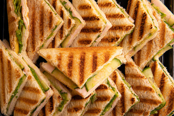 triangle sandwiches on grilled bread with ham, vegetables and cucumber. top view