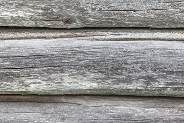 Wall made of old wooden gray logs.Rough textured surface with horizontal seams.Soft focus.Concept of decoration,vintage design of background.