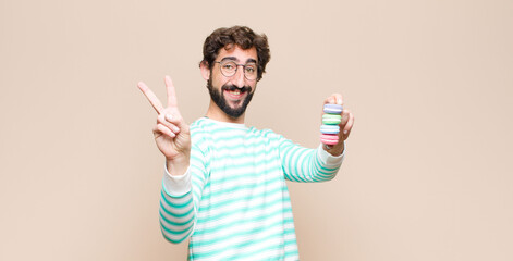 young man with macaroons against flat wall