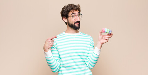 young man with macaroons against flat wall