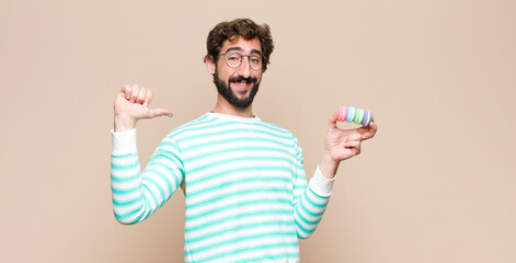 young man with macaroons against flat wall