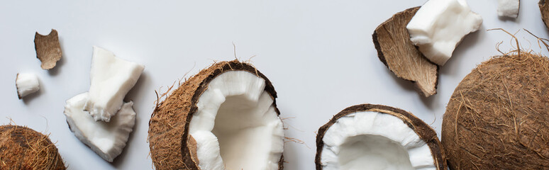 top view of fresh tasty whole and cracked coconuts on white background, panoramic shot