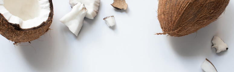 top view of whole and cracked tasty coconut half and pieces on white background, panoramic shot