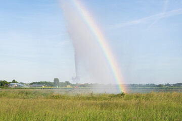 Bright rainbow caused by diffraction of sunlight in water droplets of the sprinkler system