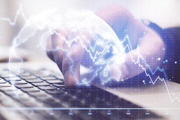 Hand using laptop and recession chart with digital earth hologram
