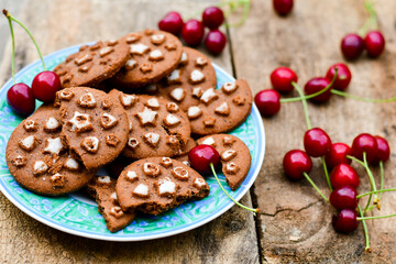  Cherries and cocoa cookies with  vanilla star decoration on wooden background. Summer dessert