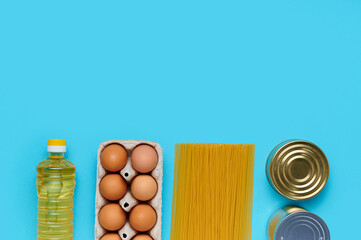 Top view, flatlay. Set of products on the blue background. Food from the store. Sunflower oil, eggs, canned food, pasta. Delivery and donation concept