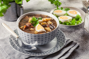 The sour soup made of rye flour with mushrooms served with eggs