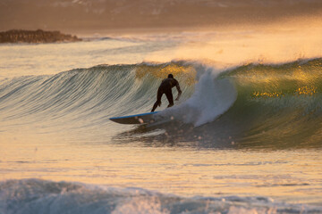 Japan surfing , sometimes during a typhoon, there are many waves in Japan especially in Hebara, Katsuura, Chiba. Westerner surfs large waves. Sunrise & at the beach with a surfer & his surf board.