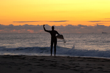 Japan surfing , sometimes during a typhoon, there are many waves in Japan especially in Hebara, Katsuura, Chiba. Westerner surfs large waves. Sunrise & at the beach with a surfer & his surf board.