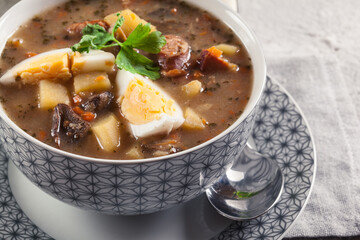 The sour soup made of rye flour with mushrooms served with eggs