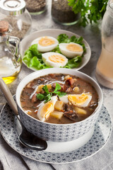 The sour soup made of rye flour with mushrooms served with eggs