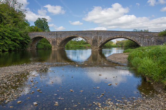 Large stone bridge crossing the river Ribble at Brungerley park, Clitheroe. Low water in summer exposing pebbles.