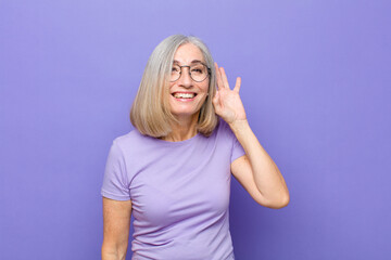 senior or middle age pretty woman smiling, looking curiously to the side, trying to listen to gossip or overhearing a secret