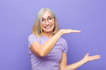 senior or middle age pretty woman holding an object with both hands on side copy space, showing,...
