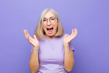 senior or middle age pretty woman feeling shocked and excited, laughing, amazed and happy because of an unexpected surprise