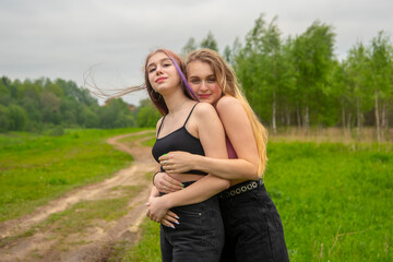 Two teenage girls with long hair on a walk hug each other.