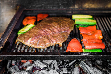 Grilling marinated angus beef flank steak on hot coals barbecue grill.