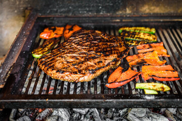 Grilling marinated angus beef flank steak on hot coals barbecue grill.