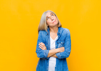 senior or middle age pretty woman shrugging, feeling confused and uncertain, doubting with arms...