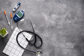 Digital glucometer, lancet pen, stethoscope and syringes on a gray background with space for text, flat lay. Diabetes concept. Blood glucose meter.