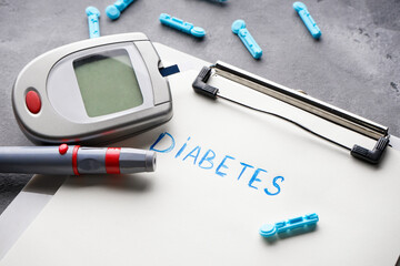 Digital glucometer, lancet pen on gray background, close-up. Diabetes concept, medical technology.