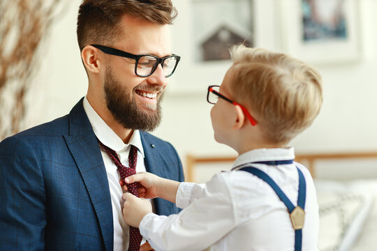 happy son helps father tie a necktie at home.