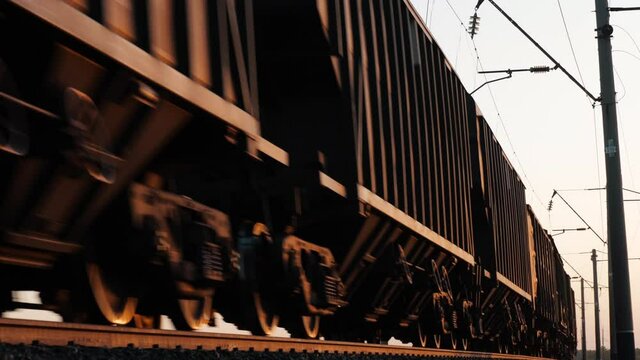 Freight train moves, carry containers, delivers wagon row with cargo. Industrial transportation of goods, heavy business transit, merchandise commercial delivery. Intermodal railway logistics closeup