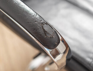 Torn and battered leather on a black office computer chair. Restoration and restoration of the...