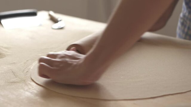 Slow motion process of homemade vegan farfalle pasta with durum wheat flour. The cook uses a rolling pin to stretch the dough, traditional Italian pasta - Woman cooks the food in the kitchen