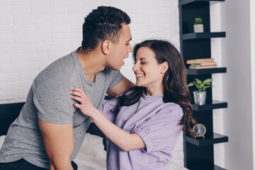 Naklejka premium bi-racial man hugging cheerful girl in bedroom