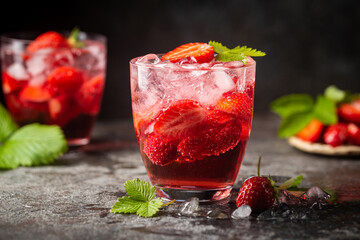 Refreshing summer drink with strawberry slices in glasses on dark background