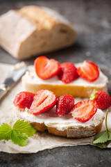 Strawberries sandwiches with cream cheese and on paper, gray background