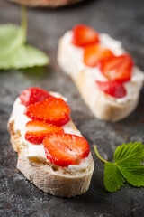 Strawberries sandwiches with cream cheese and on paper, gray background