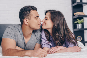 side view of cheerful and young multiracial couple with closed eyes